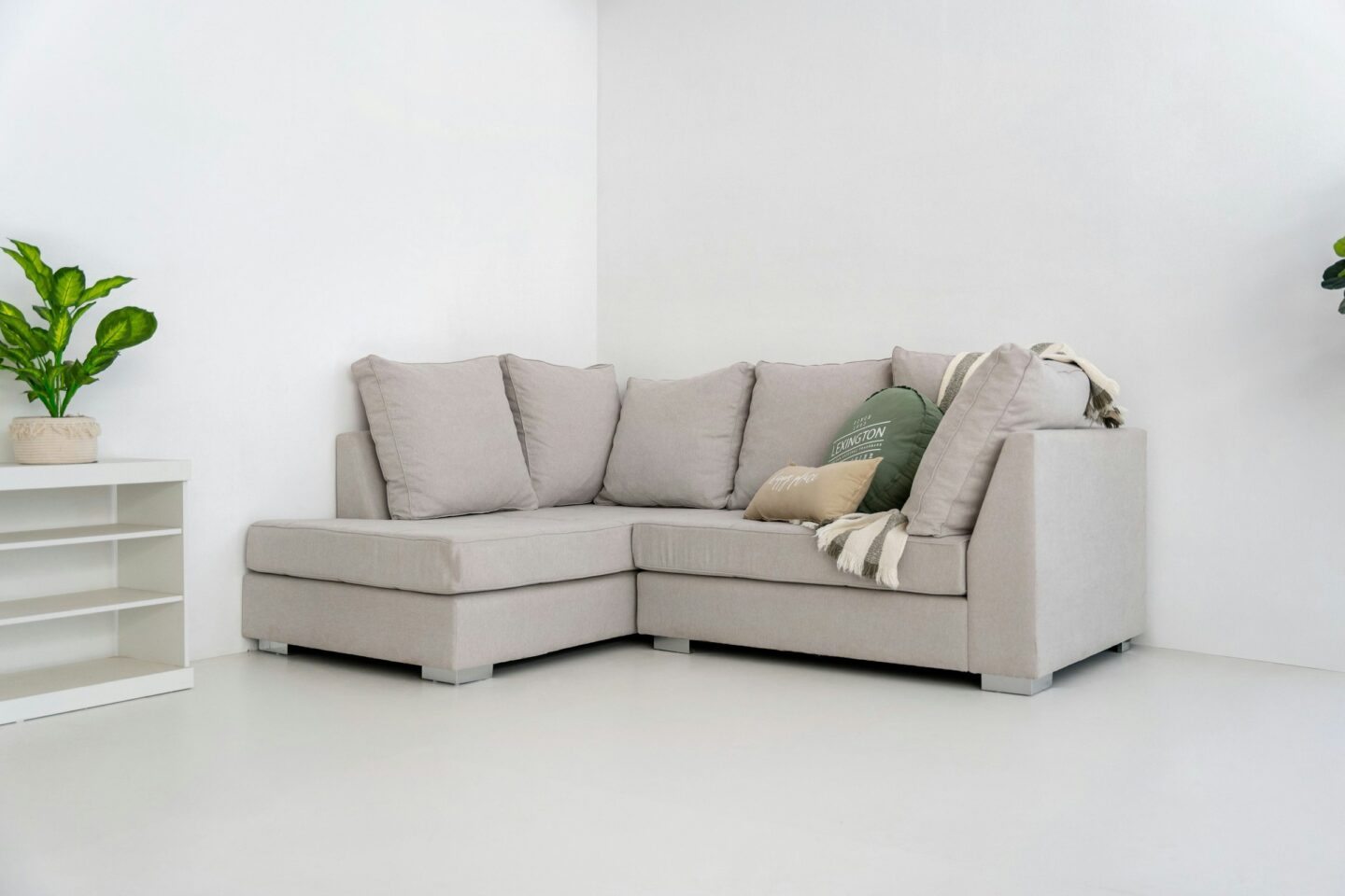 A light gray sectional sofa with pillows and blanket